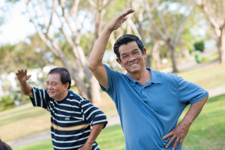 Smiling aged men doing exercises outdoorsの写真素材