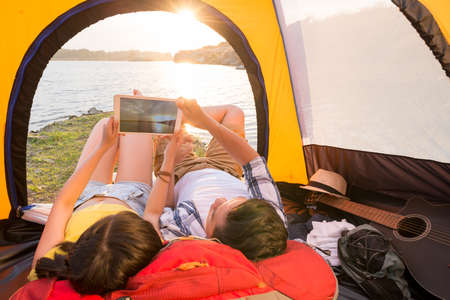 Campers taking photo of sunset on digital tabletの写真素材