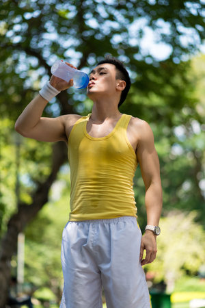Thirsty Vietnamese runner drinking water from sport bottleの写真素材