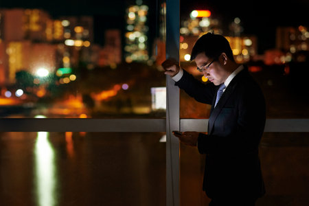Businessman looking at glowing screen of his phoneの写真素材