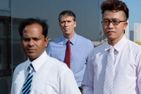 Group of successful business people standing outdoors, focus on mature leaderの写真素材