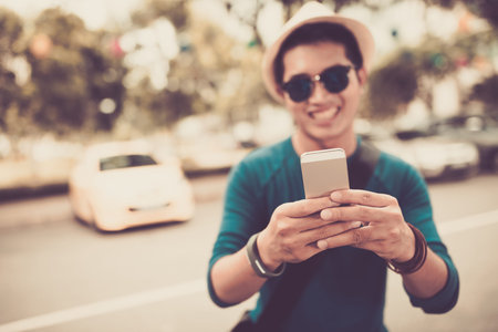 Smiling man taking selfie, focus on smartphoneの写真素材