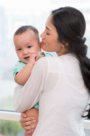 Portrait of Vietnamese young woman standing with little child in handsの写真素材