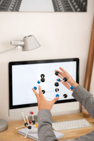 Hands of male scientist holding molecular model