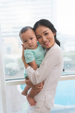 Beautiful young woman holding her baby boy