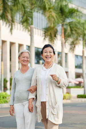 Happy senior female friends walking in the cityの写真素材