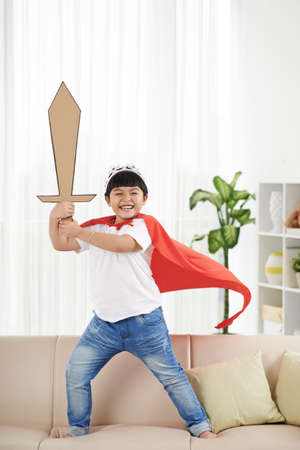 Happy Vietnamese boy with big cardboard sword pretending to be a knightの写真素材