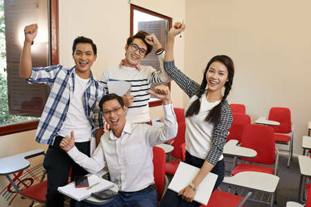 Happy excited middle-aged student among younger classmatesの写真素材