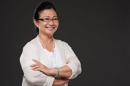 Cheerful pretty aged woman standing with her arms folded
