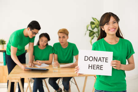 Charitable organization volunteer showing donate here boardの写真素材