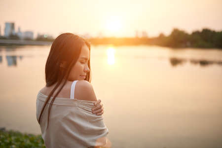 Attractive Asian girl against sunset at the riverの写真素材