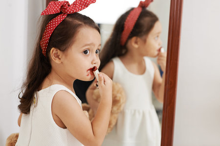 Mixed-race little girl applying red lipstickの写真素材