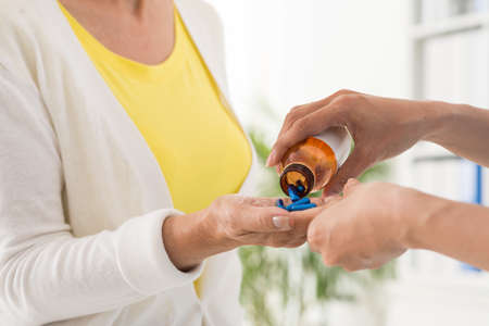 Therapist giving medicine to mature patientの写真素材