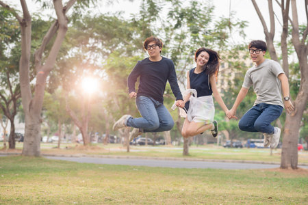 Korean friends holding hands when jumping outdoorsの写真素材