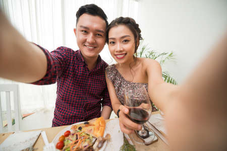 Beautiful Vietnamese couple taking selfie at party tableの写真素材