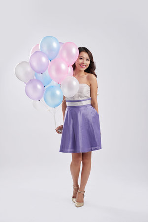 Beautiful Vietnamese young woman holding bunch of balloonsの写真素材