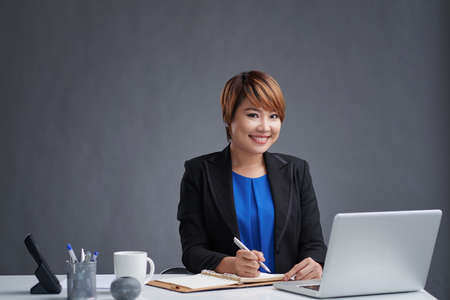 Female entrepreneur making notes in her reminderの写真素材