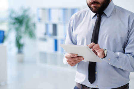 Cropped image of businessman using tablet computer in the office