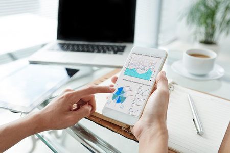 Hands of business person analyzing financial chart in her phone