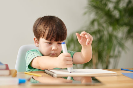 Concentrated little boy drawing with marker