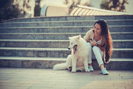 Laughing young woman patting her eskie dogの写真素材