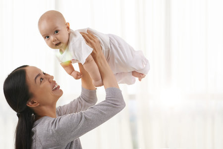 Cheerful mother playing her little baby