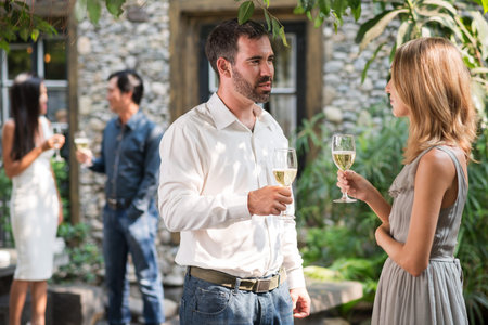 Man and woman chatting at outdoor cocktail partyの写真素材