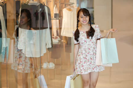 Girl posing with paper bags at the shop windowの写真素材