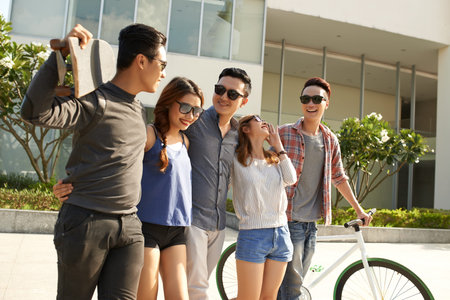 Young people in sunglasses with skateboard and bicycle standing outdoors