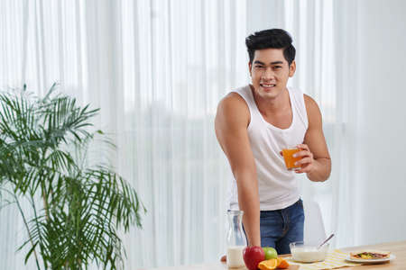 Smiling fit Vietnamese man standing at table with healthy breakfastの写真素材