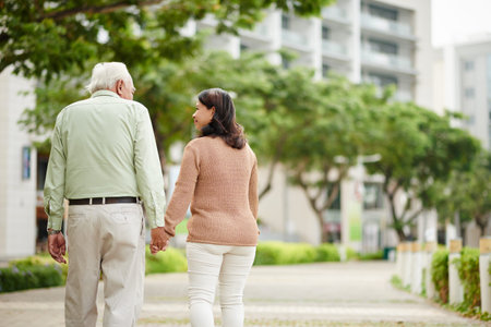 Aged couple holding hands when walking in the parkの写真素材