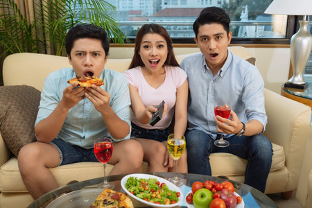 Shocked Vietnamese young people watching something on tv