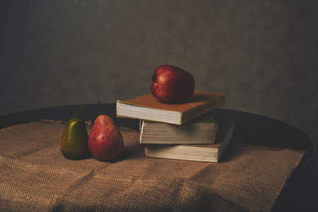 Pears, apple and stack of books on tableの写真素材