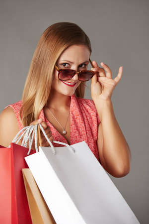Pretty woman with sunglasses and shopping bags looking at cameraの写真素材