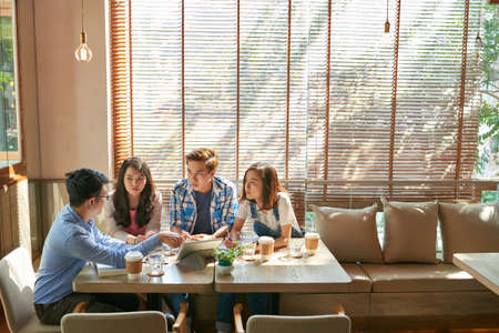 Young man showing his idea on tablet computer to fellow studentsの写真素材