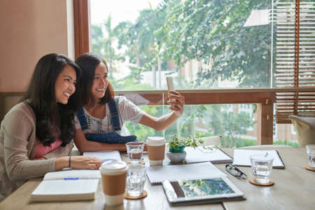 Vietnamese female students taking selfie in cafeの写真素材