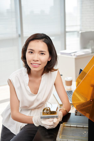 Portrait of female designer holding a sample she made with 3D printerの写真素材