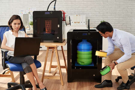 Designer looking how 3D printer making big plastic bottleの写真素材