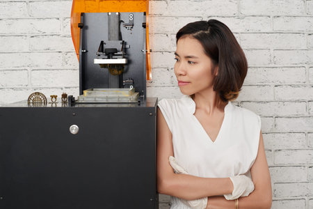 Young Asian woman looking at her small jewelry collection on 3D printer