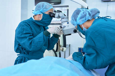 Surgeons using modern equipment during operation on eyeの写真素材