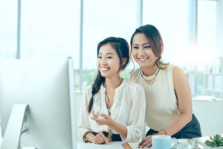 Two colleagues looking at computer screen and smilingの写真素材