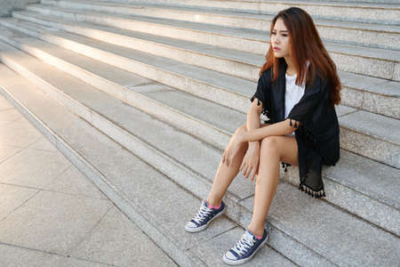 Asian pretty girl resting on stairs on the streetの写真素材