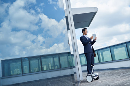 Asian man with touchpad networking on roof of modern skyscraperの写真素材