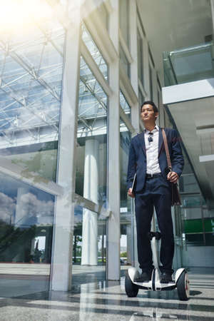Young specialist on segway moving to officeの写真素材