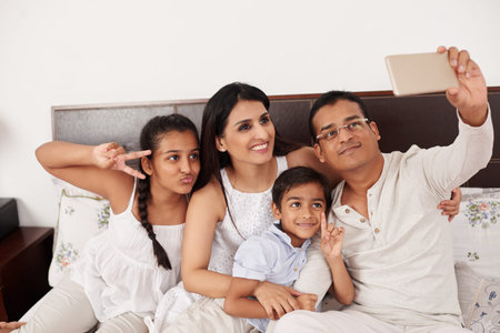 Happy Indian family taking selfie at homeの写真素材