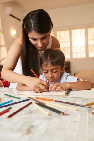 Hispanic teacher supervising little kid doing homeworkの写真素材