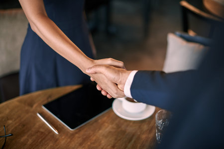 Close-up of handshake of colleagues meeting in cafe