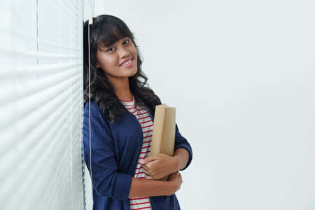 Smiling pretty girl holding a book and smilingの写真素材