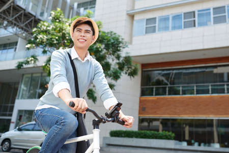 Cheerful Asian guy enjoying ride in the cityの写真素材