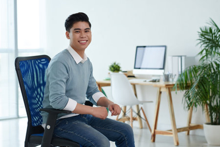 Happy business executive sitting in chair in officeの写真素材